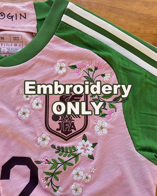 Rosa och grön fotbollströja med detaljerade blombroderier och klubbemblem.