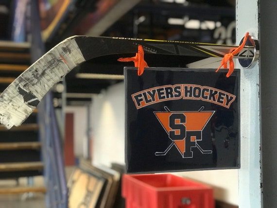 Flyers Hockey-skylt upphängd på en ishockeyklubba i ett klubbhus.