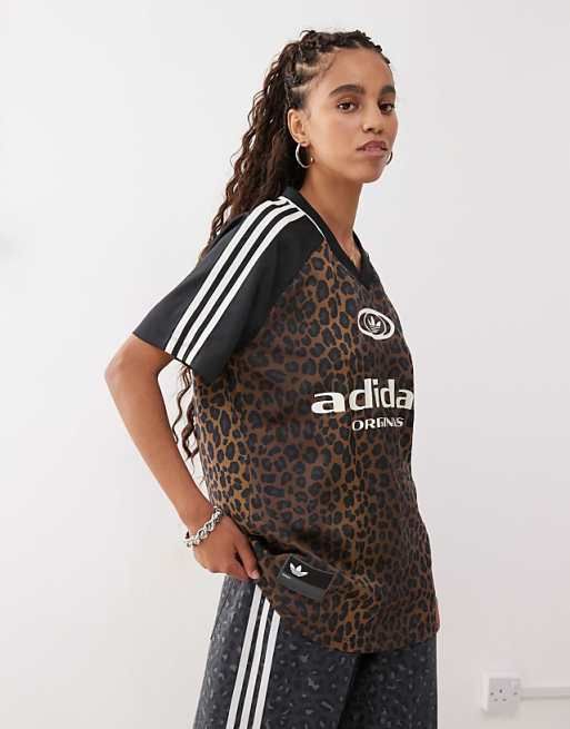 Kvinna i en mönstrad Adidas-tröja med logotyptryck för sport och fritid.