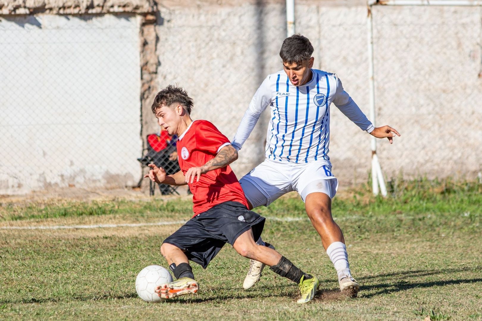 Två fotbollsspelare kämpar om bollen i en närkamp på planen