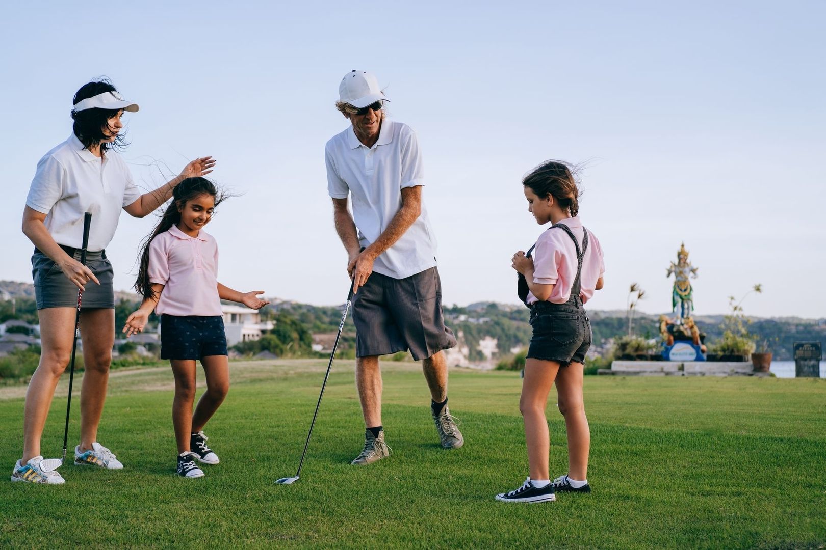 Fyra personer samlas på en gräsplan med golfklubbor