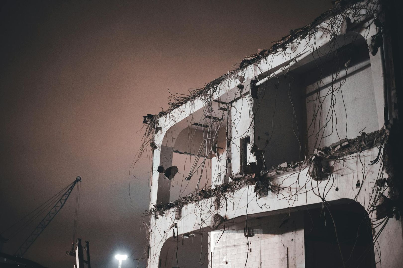 En delvis riven betongbyggnad med exponerad armering under en mörk natthimmel.